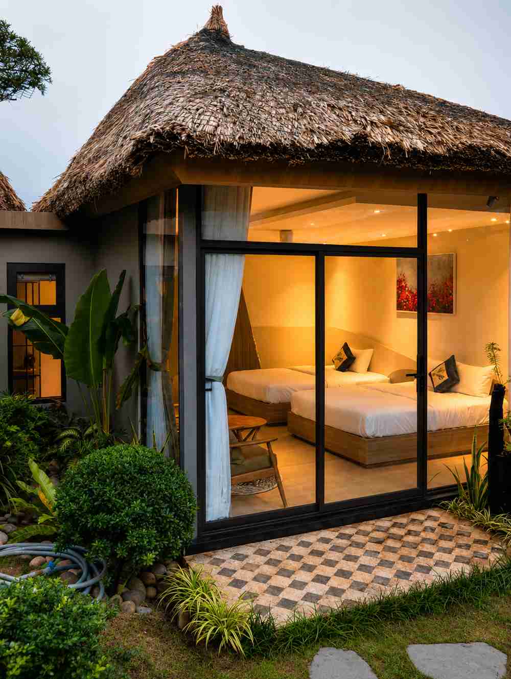 Thatched-roof bungalow at An Tùng Retreat lit at dusk